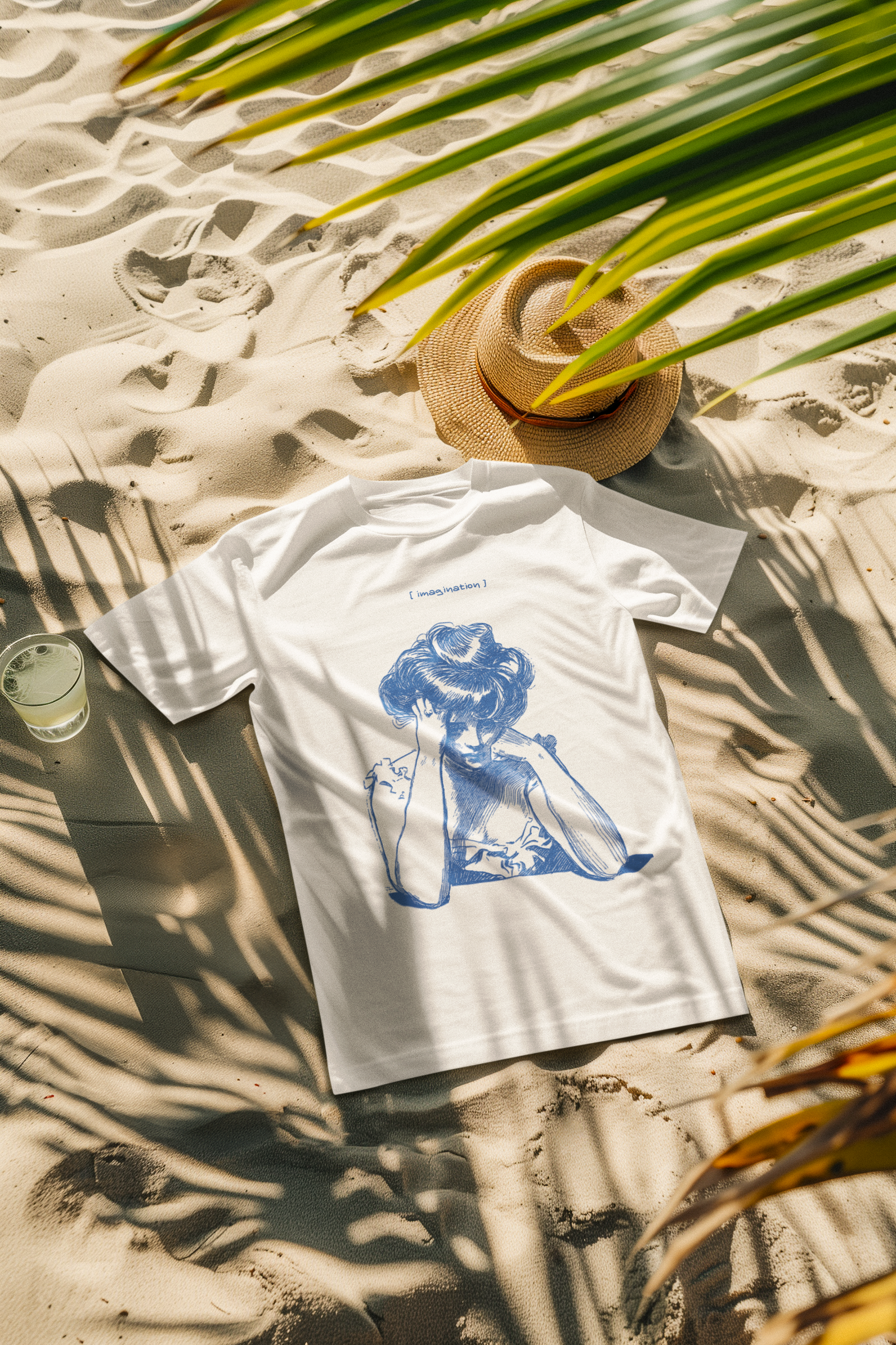 METRO ALIEN white premium quality graphic tee with blue artistic design on sand next to straw hat